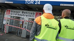 Mitarbeiter stehen vor einem Ford-Werkstor.