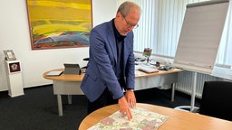 Mann steht vor Tisch mit Stadtplan