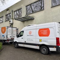 Ein Lieferwagen und ein LKW von der Tafel stehen vor einem Gebäude
