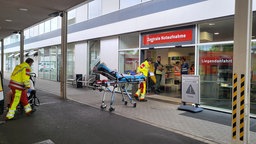 Rettungskräfte schieben ein Bett und einen Rollstuhl.