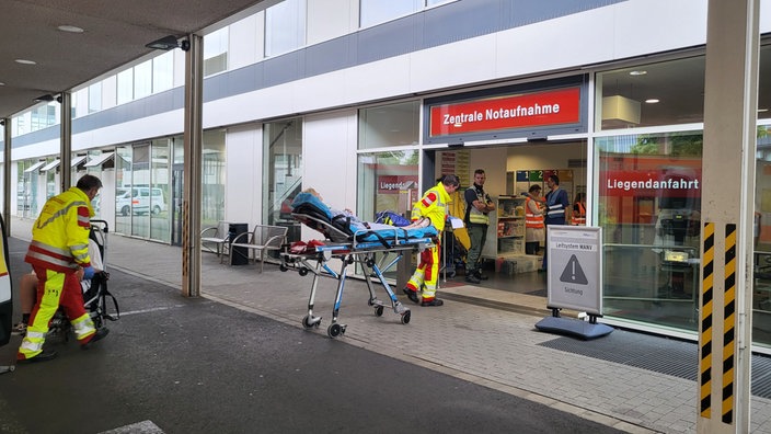 Rettungskräfte schieben ein Bett und einen Rollstuhl.