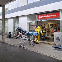 Rettungskräfte schieben ein Bett und einen Rollstuhl.