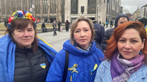Drei Frauen auf der Dome. Zwei von ihnen Tragen Anstecker oder Symbole in den Farben der ukrainischen Flagge