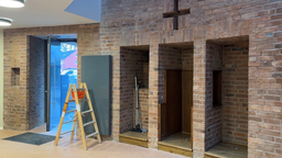 Eingangsbereich der Kirche mit leer geräumten Beichtstühlen, ist denen ein Staubsauger steht