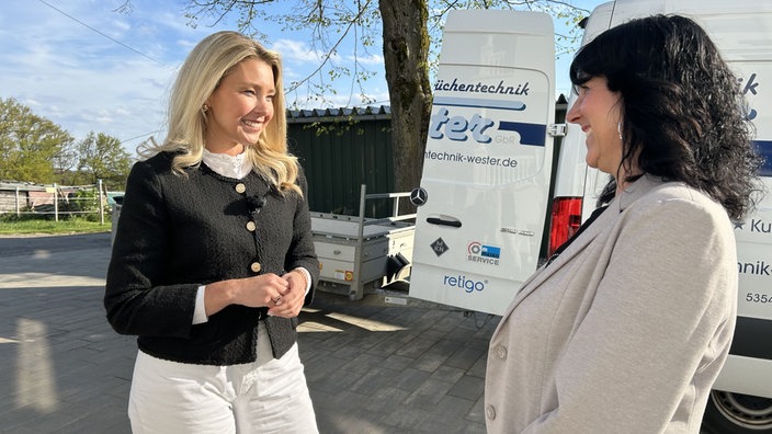 Eine junge blonde Frau im Gespräch mit einer dunkelhaarigen Frau