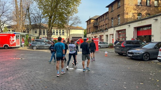 Eine Gruppe Jogger auf dem Innenhof der Feuerwehrwache 1 in Düsseldorf beim Urban Trail