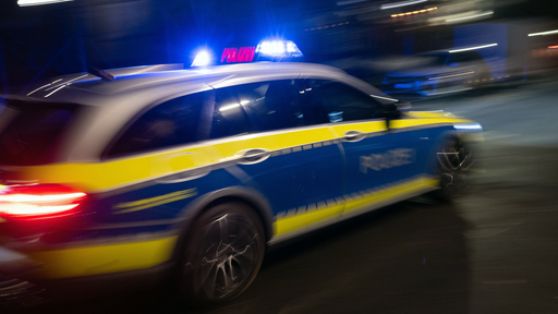 Polizeiauto mit Blaulicht fährt auf innerstädtischer Straße bei Nacht