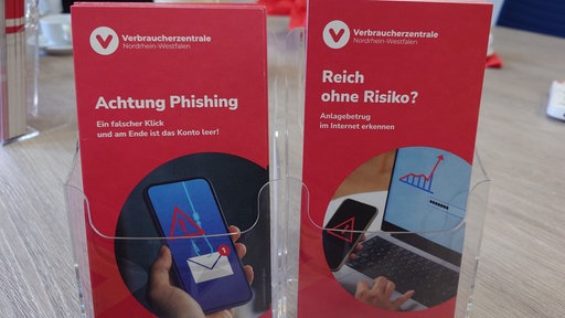 Zwei Schilder einer Aufklärungskampagne zu Internetbetrug. Darauf steht "Achtung Phishing" und die Frage "Reich ohne Risiko?"
