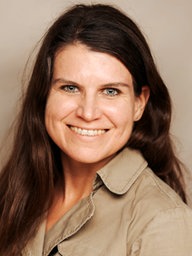 Eine Frau mit langen braunen Haaren, Katrin Peter, lächelt in die Kamera.