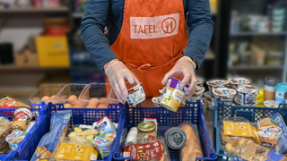 Symbolbild: Ein Tafel-Mitarbeiter füllt Körbe mit Lebensmitteln
