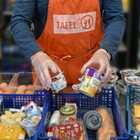 ein Tafel Mitarbeiter füllt Körbe mit Lebensmitteln