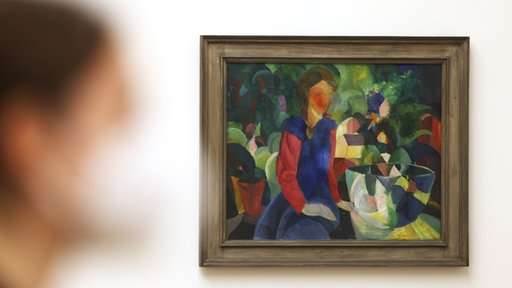 Eine Frau schaut sich das Bild "Mädchen mit Fischglas" von August Macke an