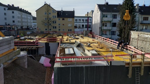 Ausgeschachtete Baustelle mit Wohnhäusern im Hintergrund