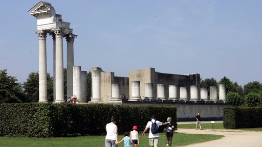 EIne Familie mit zwei Kindern ist im archäologischen Park in Xanten unterwegs, sie laufen gerade auf eine antike Ruine zu