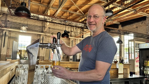 Jens Lobert zapft in seinem Rheingold-Veranstaltungssaal in Duisburg ein Bier.