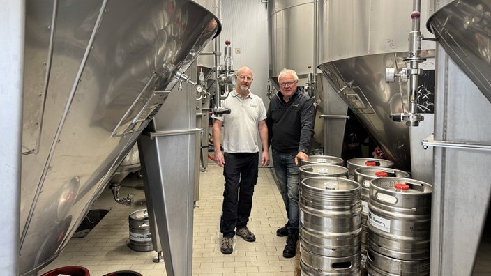 Kleine Ruhrgebiets-Brauer Jens Lobert und Christian Vormann stehen zwischen den Produktionsanlagen in der Brauerei