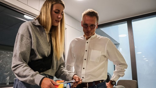 Das Bild zeigt eine Frau (Aline Dickel) und einen Herren (Henrik Freudenau) an einem Tisch mit Alufolie.