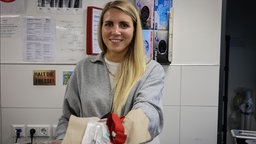 Das Bild zeigt eine Frau (Aline Dickel), die Utemsilien für eine Heroinspritze zeigt.