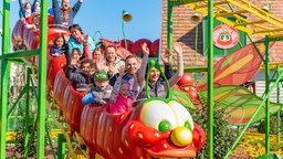 Zu sehen sind viele Menschen auf einer Raupen-Achterbahn