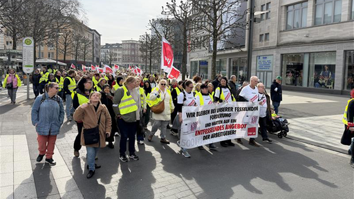 Eine große Menschenmenge zieht in gelben Warnwesten und mit Transparenten und Verdi-Fahnen durch die Bochumer Innenstadt. 