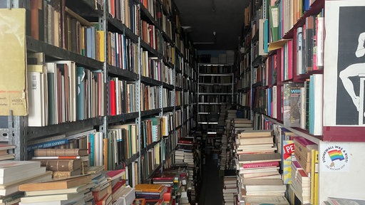 Der Laden von innen: Hier stapeln sich Bücher auch vor den Regalen. Die Regale ragen bis unter die Decke.