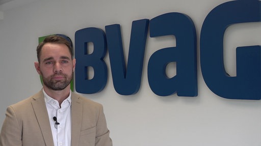 Jan Kratel, Vorstandsmitglied der BVag steht vor dem Logo der Sterbekasse.