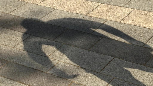 Schatten eines Mannes auf Straßenpflaster