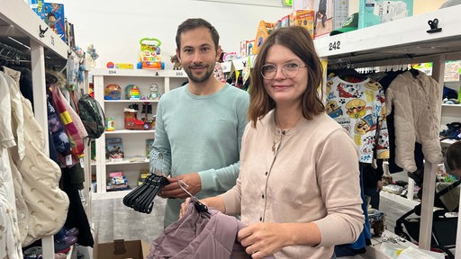 Carina und Mario Sembritzki stehen zwischen Regalen mit Spielzeugen und Kinderkleidung.