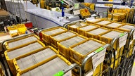 Viele gelbe Kisten mit Briefumschlägen in einem Sortierzentrum