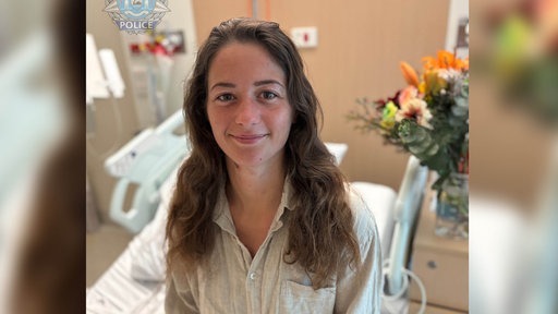 Das Portrait einer Frau, die auf einem Krankenhausbett sitzt