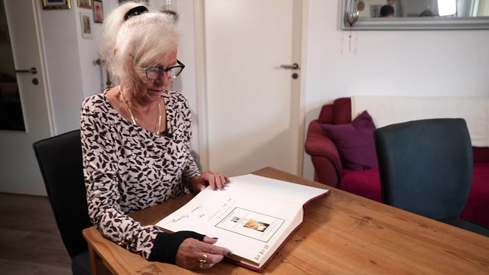 Erika Schneider sitzt an einem Tisch, vor ihr liegt ein Fotoalbum.