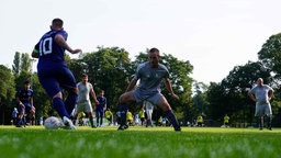 Die Teams spielen auf einem Rasenplatz im Freien gegeneinander
