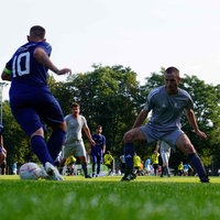 Die Teams spielen auf einem Rasenplatz im Freien gegeneinander