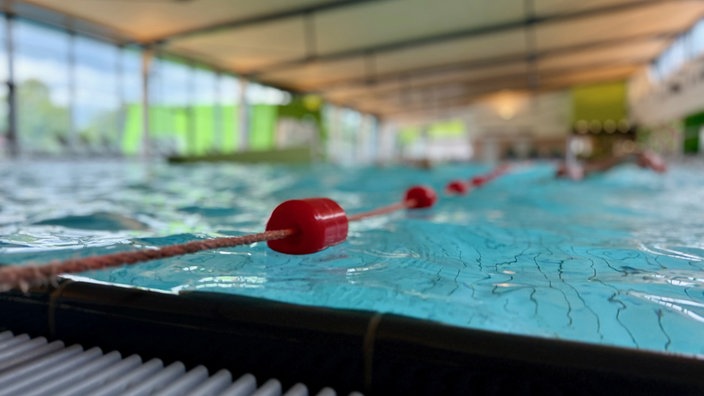 Ein Pool in einem Hallenschwimmbad, auf der Wasseroberfläche verläuft eine Bahnbegrenzung.