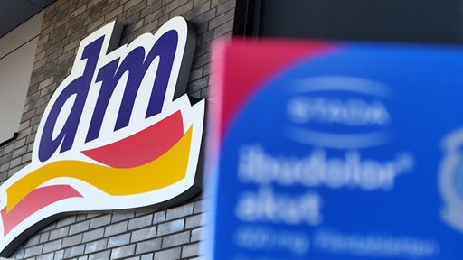 Im linken Bildausschnitt ist ein DM-Logo, rechts daneben eine Packung Schmerzmittel.
