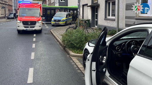 Eine geöffnete Autotür und im Hintergrund ein Polizei- und ein Krankenwagen