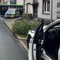 Eine geöffnete Autotür und im Hintergrund ein Polizei- und ein Krankenwagen