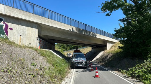 Unter einer Brücke stehen zwei Fahrzeuge.