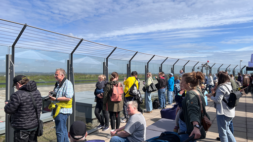 Interessierte schauen von der Besucherterrasse auf den Flugplatz Dortmund.