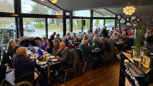 Rund 50 bedürftige Senioren sitzen an Tischen in einem italienischen Restaurant