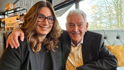 Barbara Schneider sitzt auf einer Bank im Restaurant neben Stammgast und Sponsor Heinz Stemmler