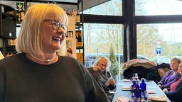 Die Vereinsvorsitzende Cornelia Sbosny lacht im Restaurant mit ihren Gästen