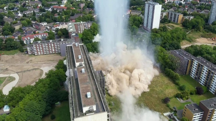 Ein Gebäude wird gesprengt, darüber eine riesige Staubwolke