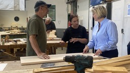Leiterin der Beratungsstelle, Martina Steffen, mit Anleiterin und Teilnehmer in der Holzwerkstatt