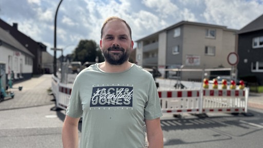 Ein Mann steht vor einer Baustelle in einem Wohngebiet