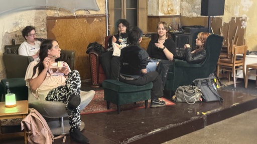Eine Gruppe junger Menschen sitzt in einem Café und unterhält sich.