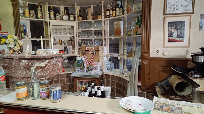 Theke in Wacholderbrennerei, Flaschen und Gläser füllen das alte, weiße Regal