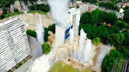 Ein weißes Hochhaus stürzt nach einer geplanten Sprengung ein