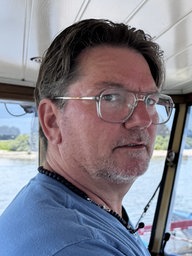 Ein Mann steht im Fahrerhäuschen eines Boots was über den Rhein fährt