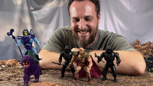 Martin Lukas schaut auf He-Man und Skeletor Actionfiguren